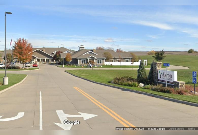 The street view of the exterior of the Akron Care Center, a sprawling grey one-story building.