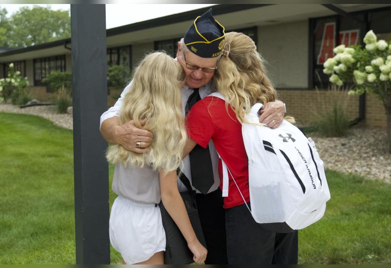 American Legion Post 186 member Keith Swanson hugs his granddaughters, Amelia Brown and Katie Brown.