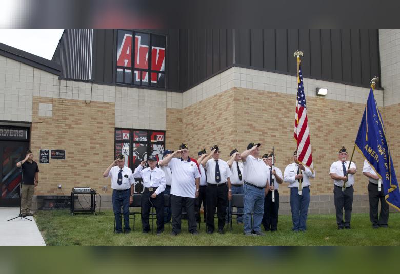 American Legion Post 186 members salute the flag as the band plays the Star Spangled Banner.
