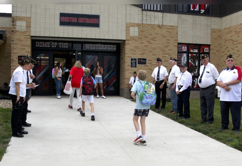 Members of the Akron Legion Post 186, as well as A-W students line the sidewalk and welcome students back for the first day.